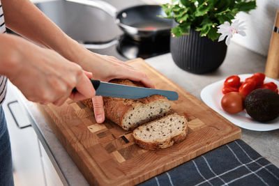 Woman cutting loaf of bread with large knife