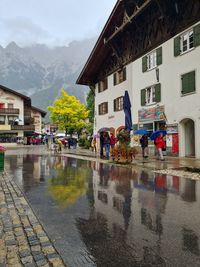 Wet street by buildings in city during rainy season