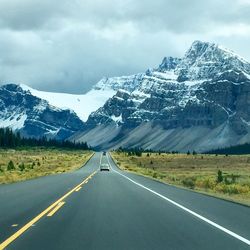 Road by mountains against sky