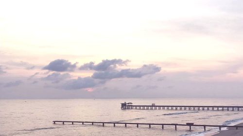 Pier over sea against sky during sunset