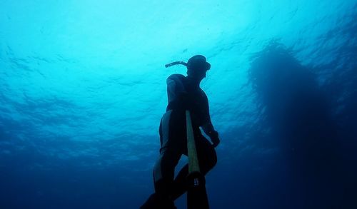Low angle view of man taking selfie with monopod in sea