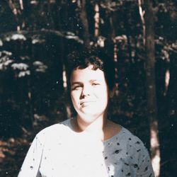 Portrait of man against tree trunk in forest