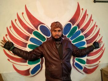 Portrait of young man standing against multi colored wall