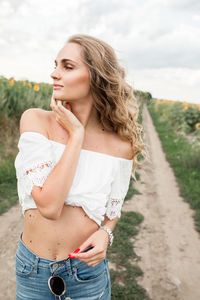 Portrait of young woman standing against trees