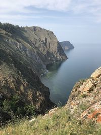 Scenic view of rocks by sea against sky