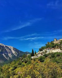 Scenic view of trees and mountains against blue sky