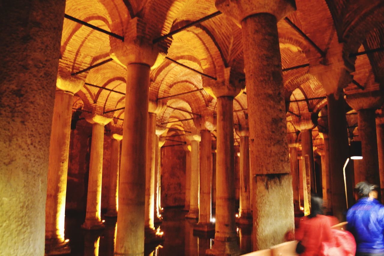 REAR VIEW OF PEOPLE IN ILLUMINATED TEMPLE BUILDING