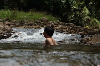 Shirtless man swimming in water