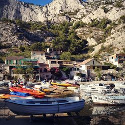 Boats moored at harbor by buildings against mountain