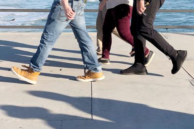 Low section of people walking on footpath by lake