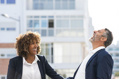 Happy business people laughing while standing outdoors