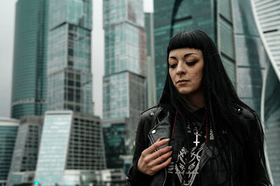 Portrait of woman standing against modern buildings in city