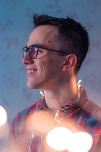 Smiling man with illuminated string lights at home