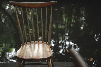 Close-up of empty chair on table against trees