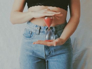 Midsection of woman holding umbrella standing against wall