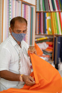 Tailor wearing protective face mask while working in shop