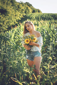  young woman holding bouquet standing in field