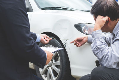 Man showing damaged car to insurance agent