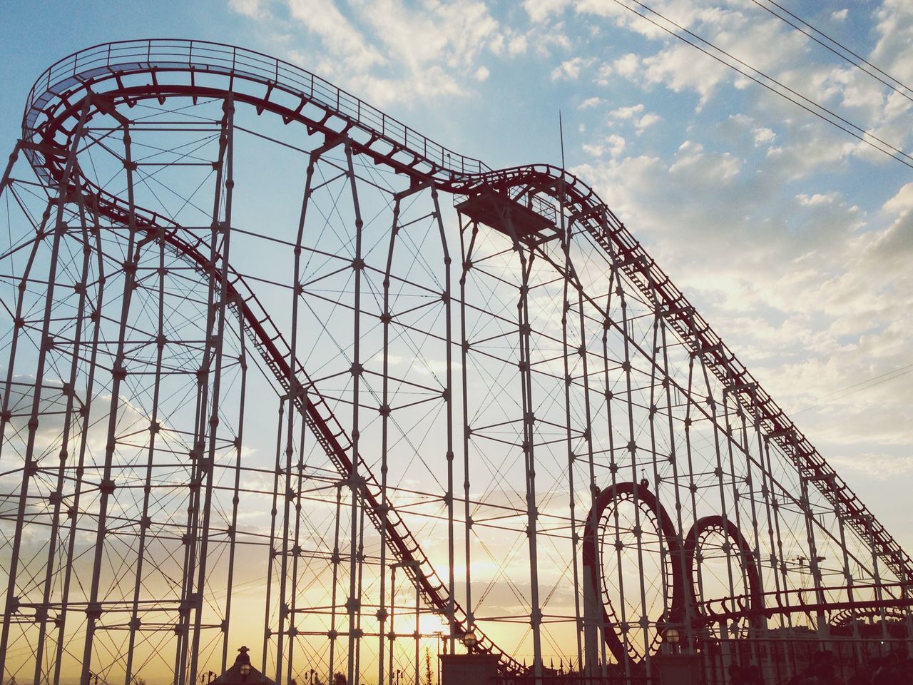 amusement park, amusement park ride, low angle view, ferris wheel, sky, arts culture and entertainment, built structure, architecture, metal, silhouette, cloud - sky, travel destinations, sunset, cloud, leisure activity, outdoors, travel, famous place, fun, rollercoaster