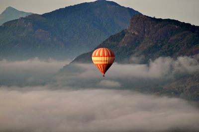 Hot air balloon flying over mountains against sky