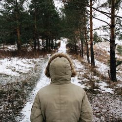 Rear view of woman standing in forest during winter