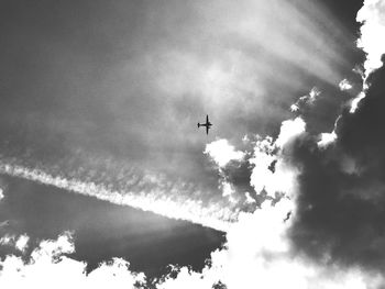 Low angle view of silhouette airplane flying against sky