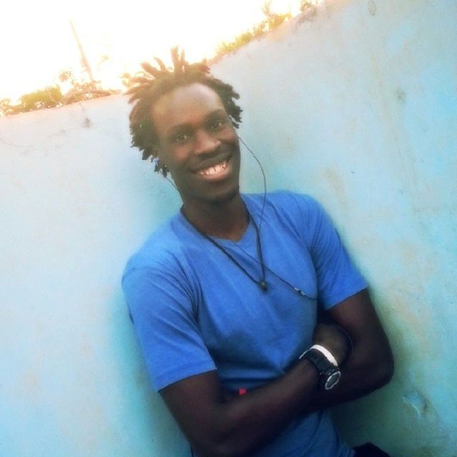 PORTRAIT OF YOUNG MAN STANDING AGAINST BLUE WALL