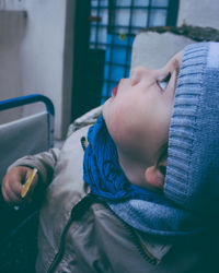 Cute baby boy holding lollipop while looking up at home