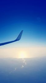 Cropped image of airplane against blue sky on sunny day