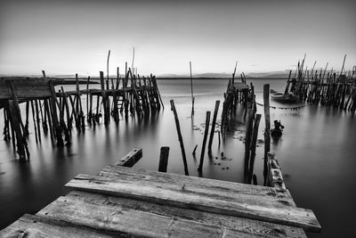 Wooden posts in sea against sky