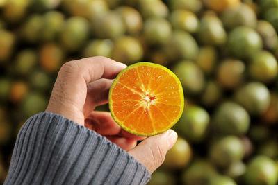 Cropped image of person holding orange