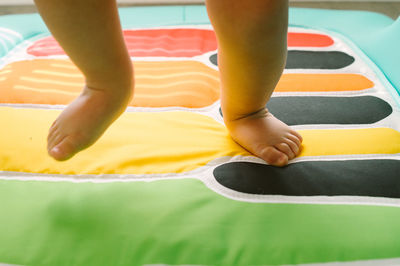 Low section of baby boy playing on piano designed mat