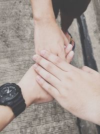 Directly above shot of friends stacking hands on footpath