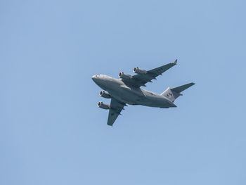 Low angle view of airplane flying against clear blue sky