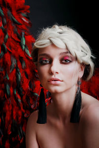 Close-up portrait of woman with make-up against black background