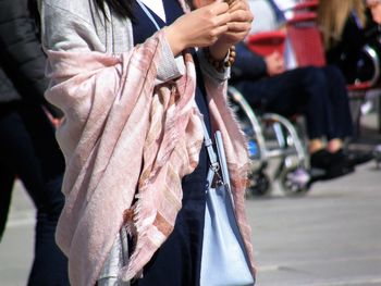 Midsection of woman standing on street in city during sunny day