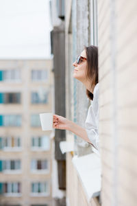Side view of young woman holding coffee cup