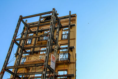 Low angle view of crane against clear blue sky