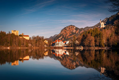 Reflection of trees and buildings in lake against sky