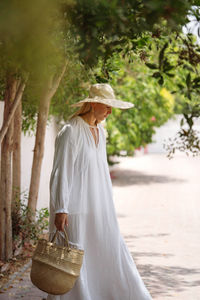 Woman wearing white dress walking in the garden barefoot