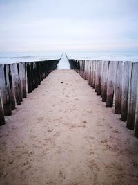 Wooden pier on sea against sky