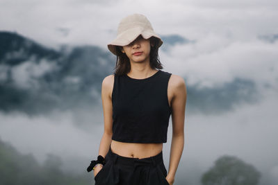 Portrait of young woman standing against sky