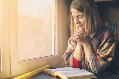 Woman looking through window at home