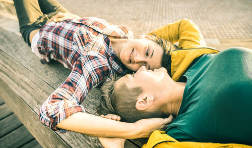 Lesbian couple lying on bench at park