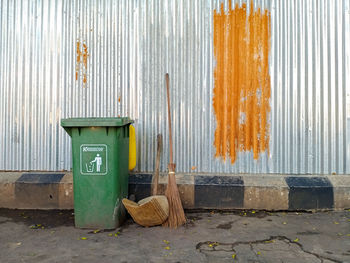 Garbage bin on footpath against wall