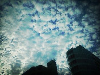 Low angle view of modern building against cloudy sky