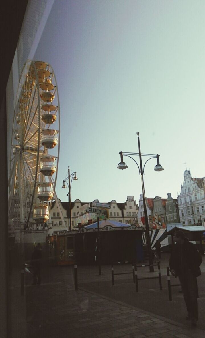 architecture, built structure, clear sky, building exterior, amusement park, amusement park ride, arts culture and entertainment, ferris wheel, city, copy space, sky, travel destinations, incidental people, large group of people, travel, famous place, low angle view, tourism, day, city life