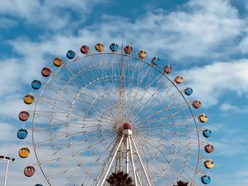 Low angle view of ferris wheel against cloudy sky