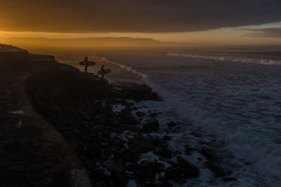 Surfers looking at sea at dusk