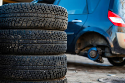 Winter tires next to the car in wheel service, seasonal tire change concept, closeup